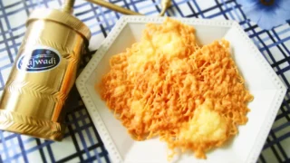 金属製ストリングホッパーで成形した、焼き色のついた米粉のクッキーが白い六角形の皿に盛られ、青いチェック柄のクロスの上に置かれている様子